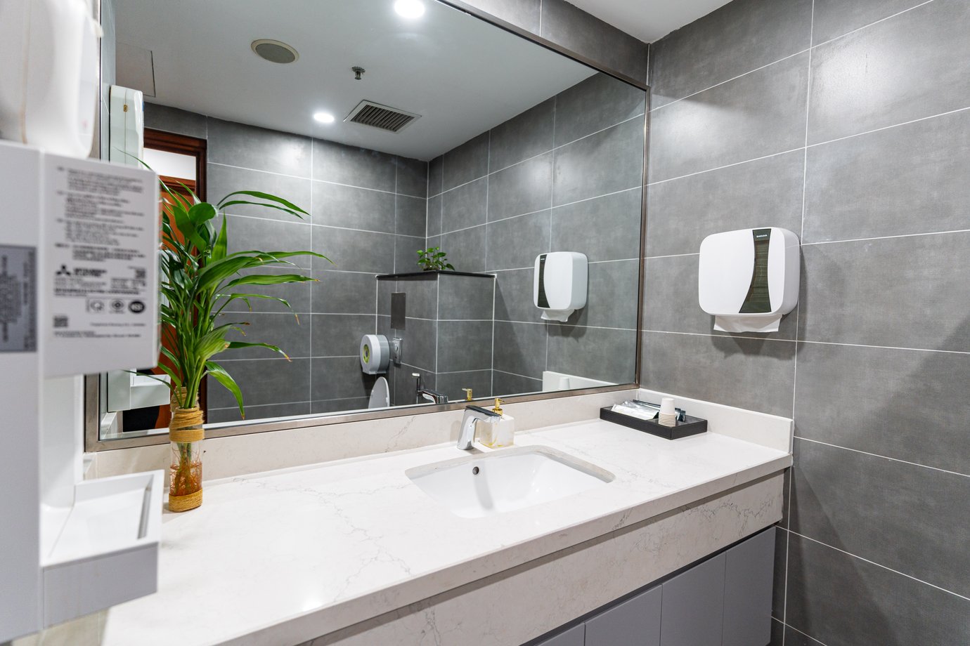 SH Premium Lounge washroom at Can Tho International Airport with modern sink, large mirror, and grey tiled walls
