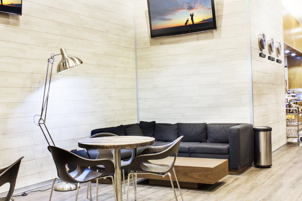 VIP Lounge by Mera at Cancun International Airport seating area with sofa, round table, lounge chairs, floor lamp, and wall-mounted TV. VIP Lounge by Mera at Cancun International Airport seating area with sofa, round table, lounge chairs, floor lamp, and wall-mounted TV.