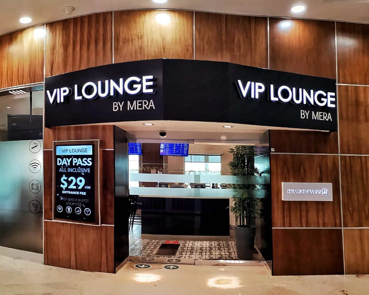 VIP Lounge by Mera at Cancun International Airport entrance, featuring illuminated signage, reception desk, and day pass pricing display. VIP Lounge by Mera at Cancun International Airport entrance, featuring illuminated signage, reception desk, and day pass pricing display.