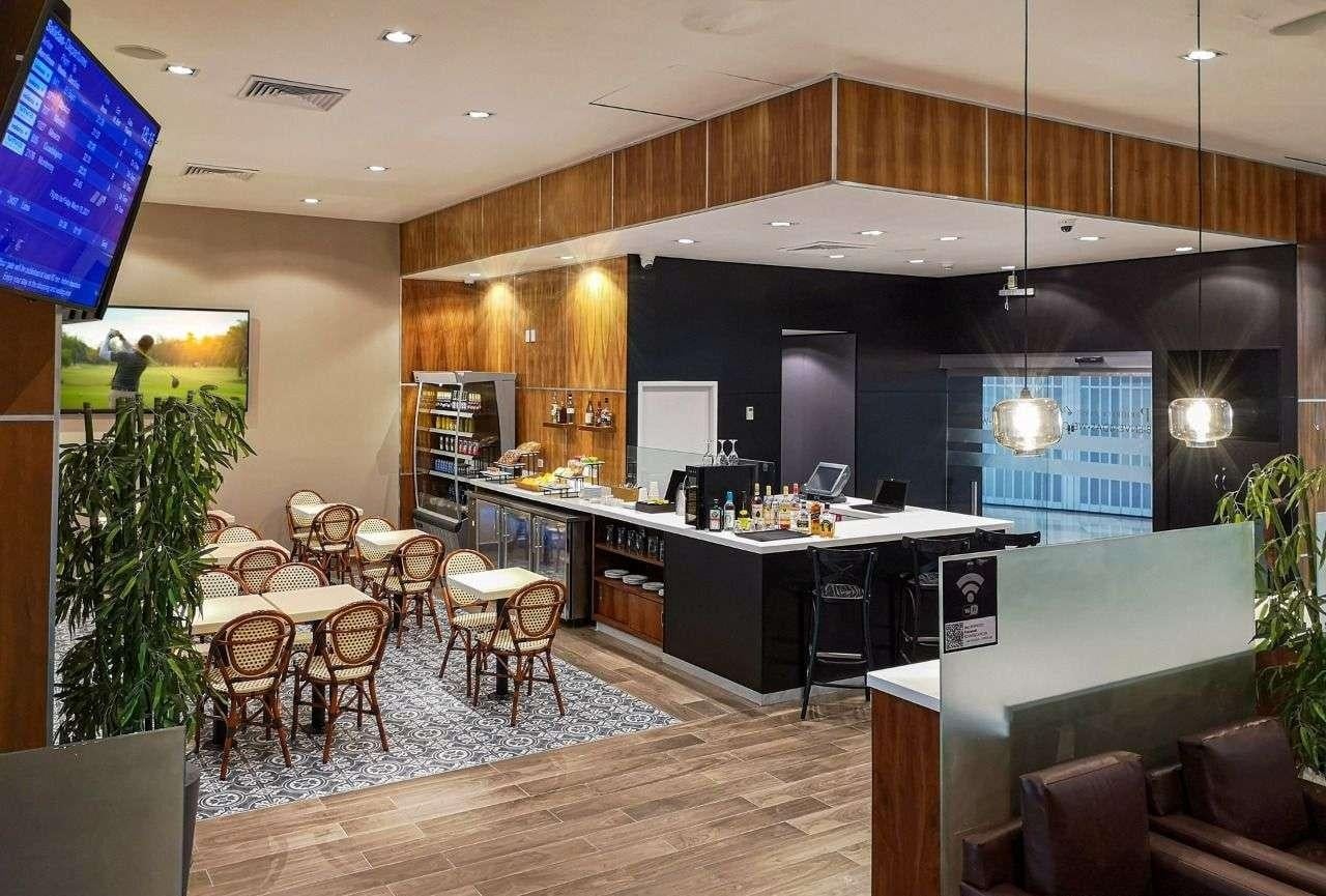 VIP Lounge by Mera at Cancun International Airport interior with bar area, dining tables, and seating in a modern lounge space. VIP Lounge by Mera at Cancun International Airport interior with bar area, dining tables, and seating in a modern lounge space.