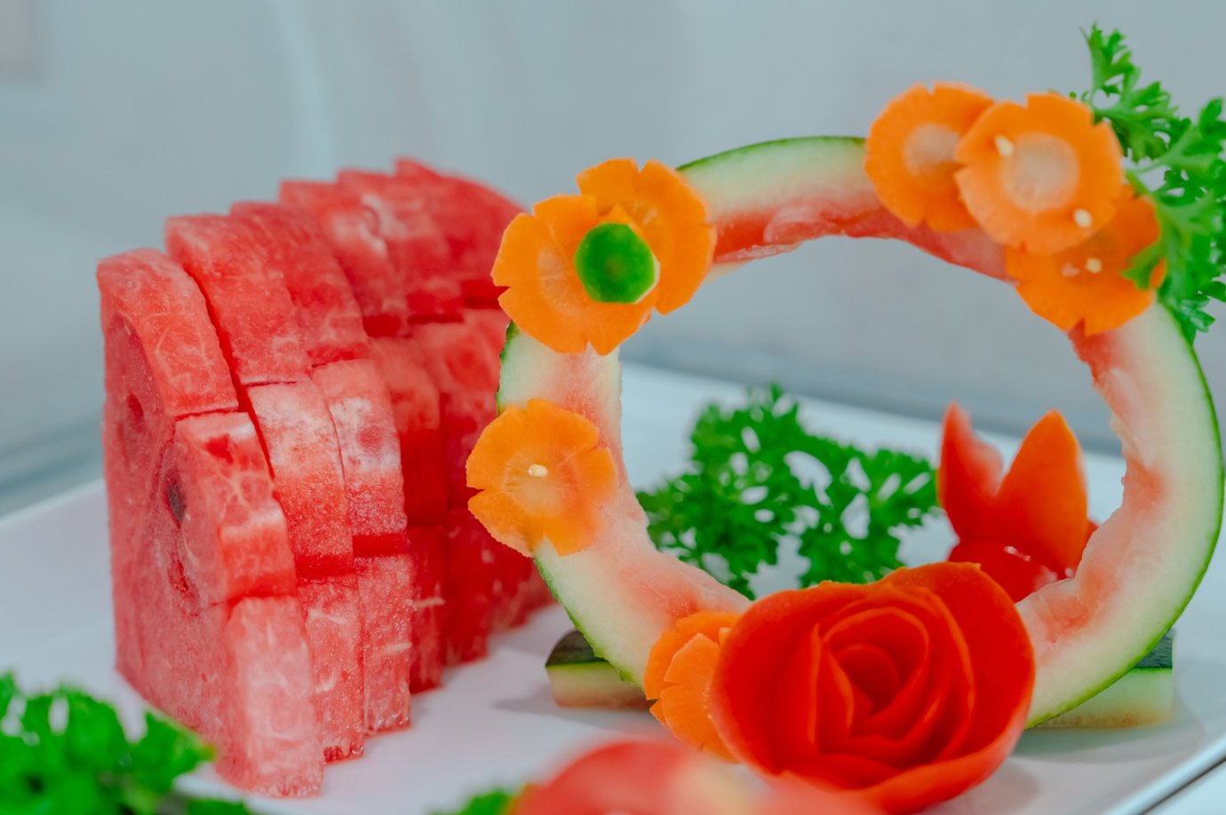 Close-up of sliced watermelon arranged with decorative fruit carving, including carrot flowers and a watermelon rind ring, displayed at SH Premium Lounge, Cat Bi International Airport (HPH).
