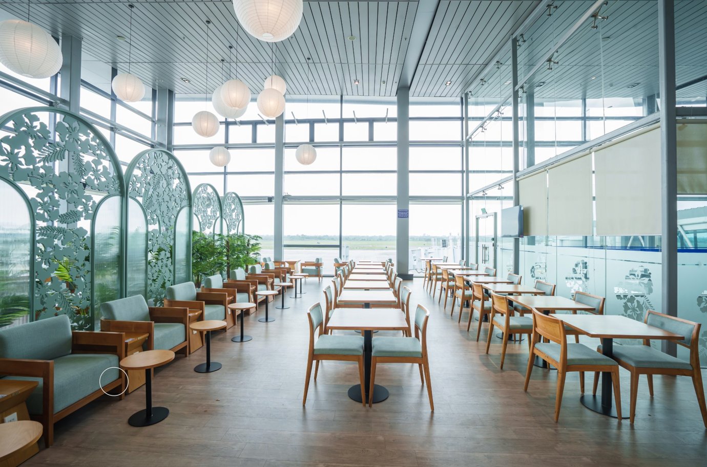 Spacious seating and dining area at SH Premium Lounge, Cat Bi International Airport (HPH), featuring large windows, runway views, modern wooden furniture, and a bright, relaxing atmosphere