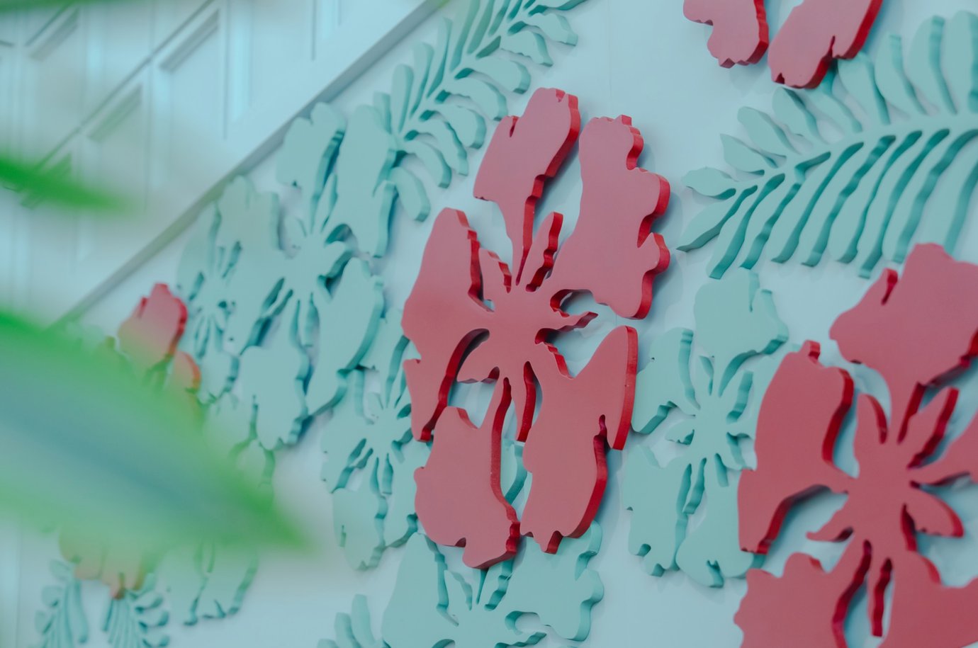 Close-up of decorative wall panel featuring layered floral cut-out patterns in red and pastel green tones at SH Premium Lounge, Cat Bi International Airport (HPH).