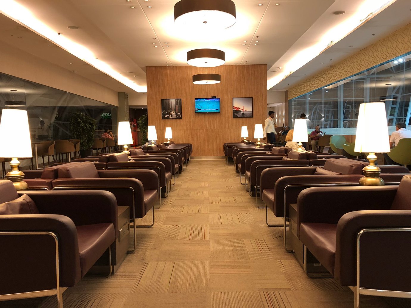 Travel Club Lounge at Chennai Airport Terminal 4 with rows of leather armchairs, warm ambient lamps, and large window views of the terminal.