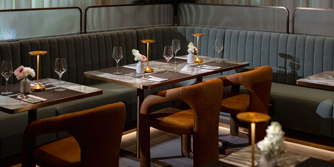 Dining section inside the Plaza Premium First Lounge at DFW Airport. The space features plush booth seating, marble-top tables, warm accent lighting, and upscale place settings Dining section inside the Plaza Premium First Lounge at DFW Airport. The space features plush booth seating, marble-top tables, warm accent lighting, and upscale place settings