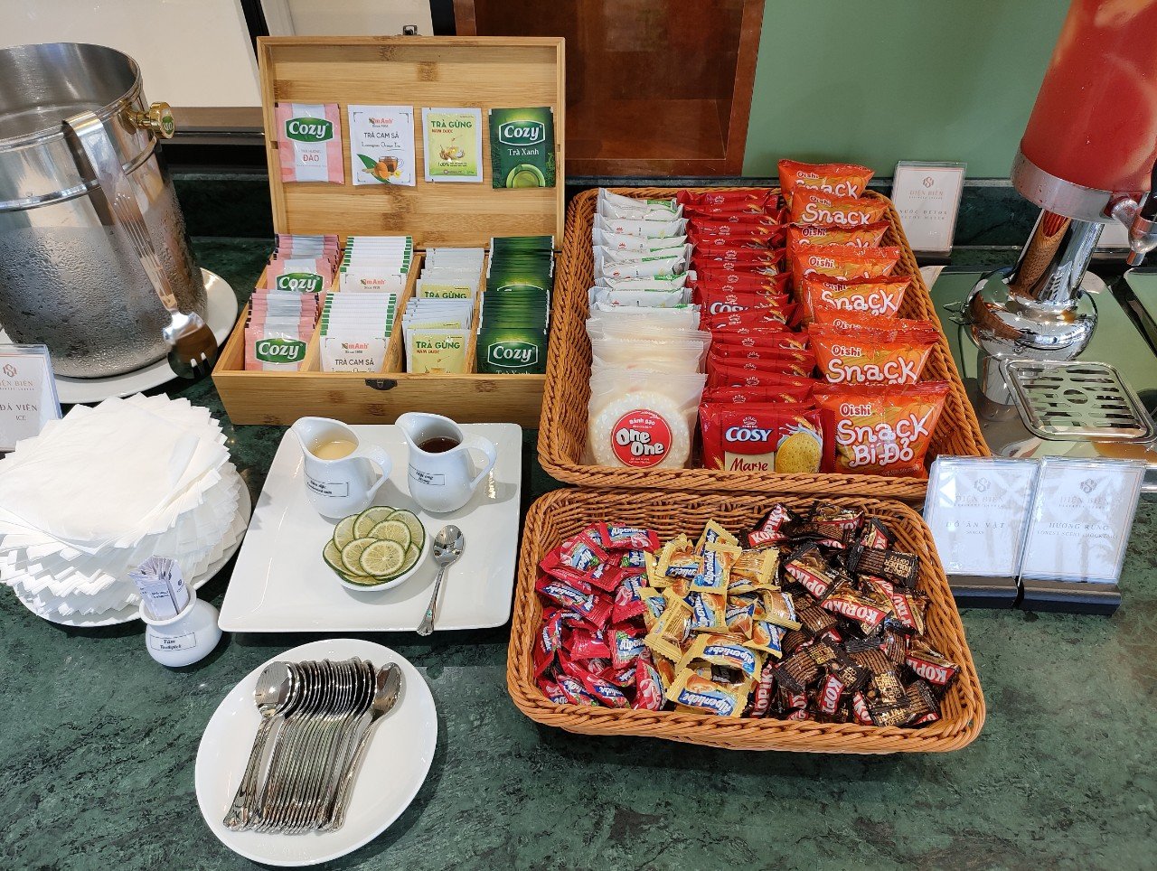 Beverage and snack station at Điện Biên SH Business Lounge, Điện Biên Phủ Airport (DIN), featuring tea selection, biscuits, candies, and self-serve refreshments for lounge guests.