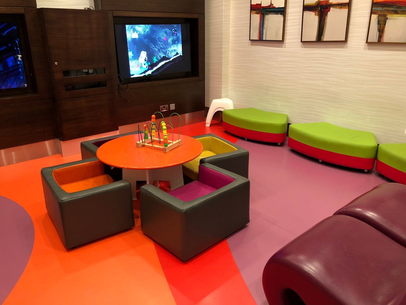 Colorful children’s play area inside the Marhaba Lounge at Dubai International Airport Terminal 1, featuring bright seating, a TV screen, and interactive toys for young travellers. Colorful children’s play area inside the Marhaba Lounge at Dubai International Airport Terminal 1, featuring bright seating, a TV screen, and interactive toys for young travellers.
