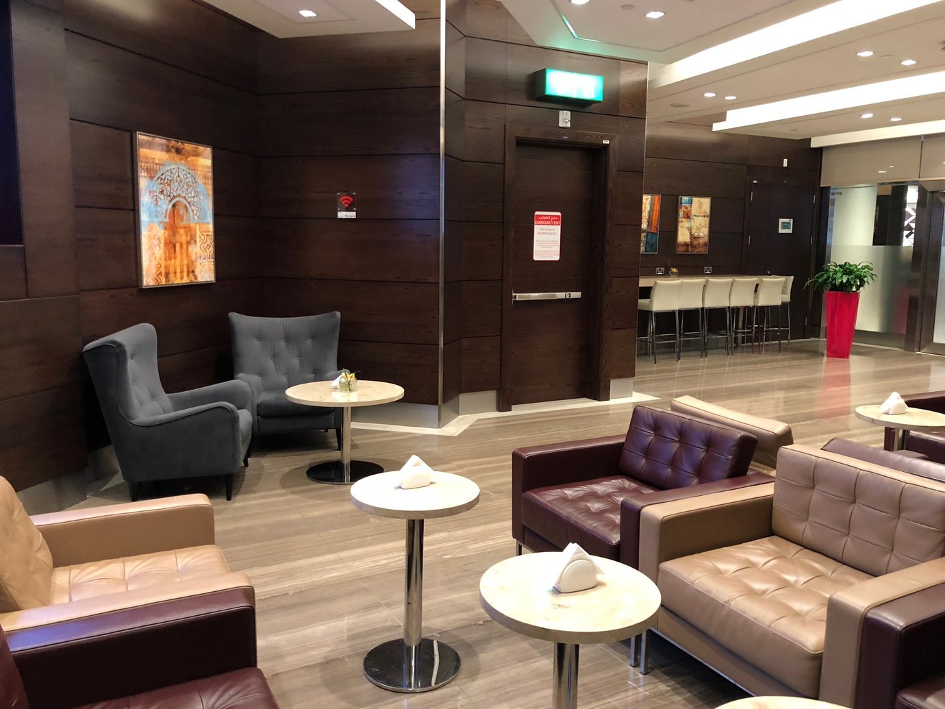 Seating area inside the Marhaba Lounge at Dubai International Airport Terminal 1, featuring modern leather armchairs, warm wooden interiors, and soft lighting for a relaxed pre-flight atmosphere. Seating area inside the Marhaba Lounge at Dubai International Airport Terminal 1, featuring modern leather armchairs, warm wooden interiors, and soft lighting for a relaxed pre-flight atmosphere.