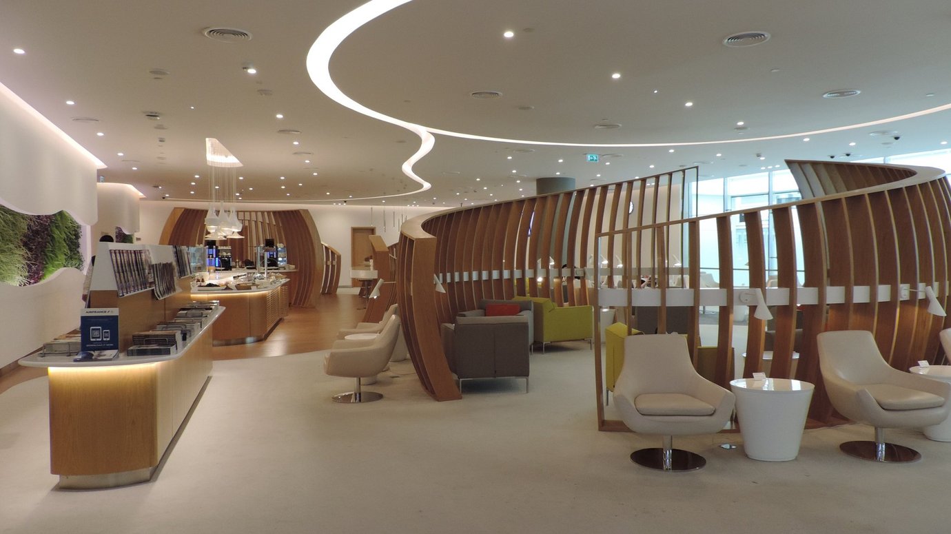 Wide view of the SkyTeam Lounge at Dubai International Airport Terminal 1, showcasing its open modern design with curved wooden partitions, bright lighting, and stylish seating areas for premium travelers. Wide view of the SkyTeam Lounge at Dubai International Airport Terminal 1, showcasing its open modern design with curved wooden partitions, bright lighting, and stylish seating areas for premium travelers.