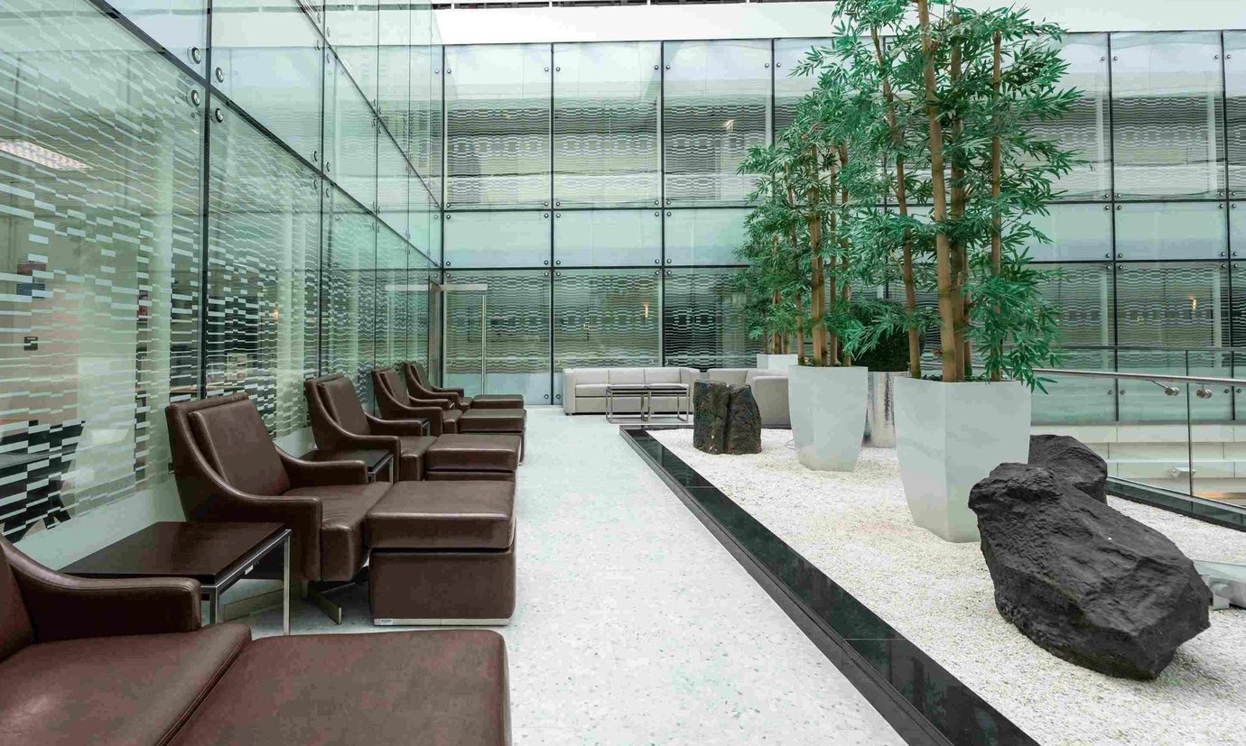 Relaxation seating area inside the Ahlan Lounge at Dubai International Airport Terminal 3 Concourse A, featuring brown leather recliners, glass walls, and indoor greenery for a calm, modern atmosphere