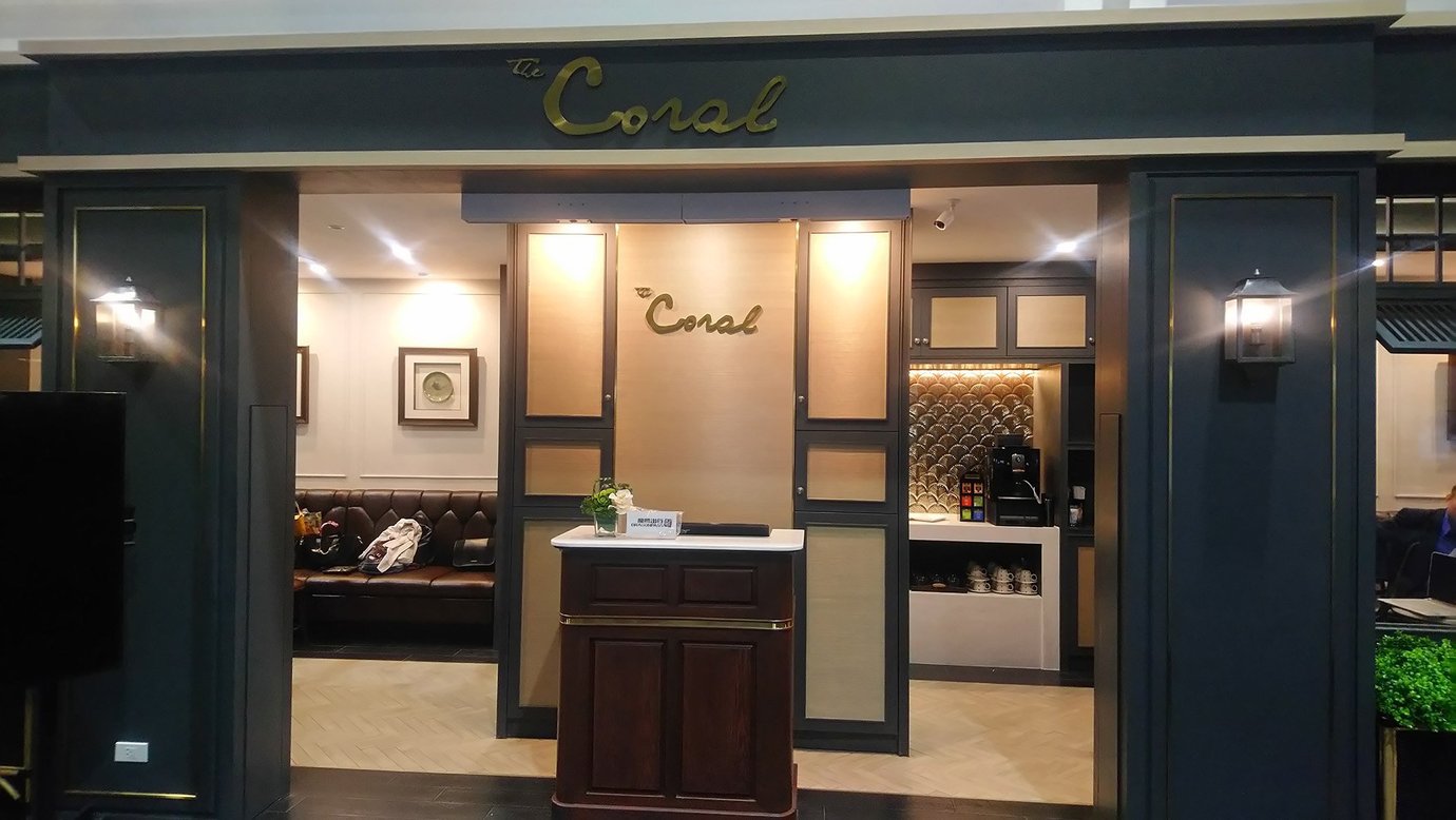 Entrance to The Coral Executive Lounge at Chiang Rai Airport (CEI), featuring elegant dark paneling, warm lighting, and a modern coffee and beverage station in a luxurious setting