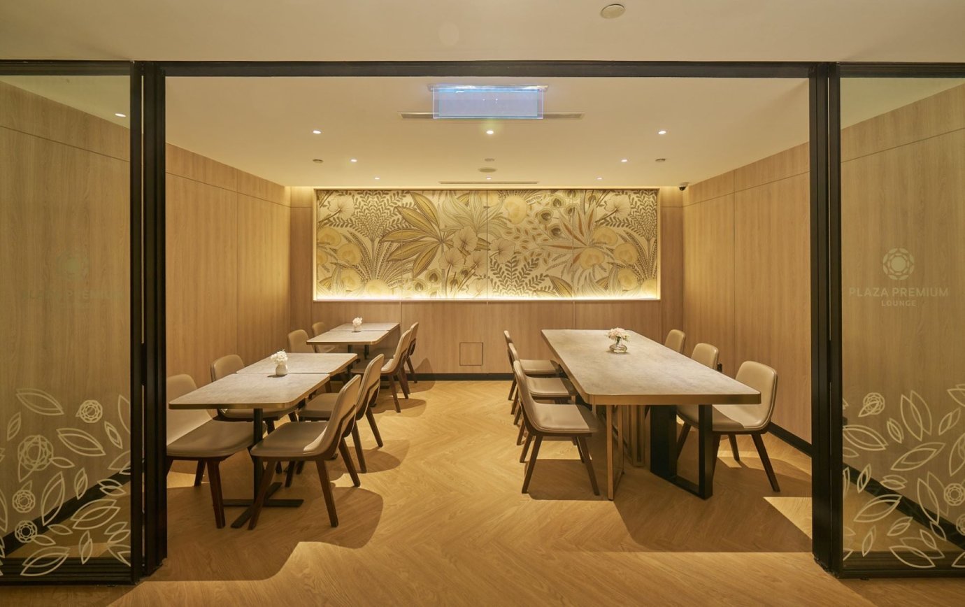 Private dining area at Plaza Premium Lounge, Langkawi Airport, with tables, chairs, and wood-accented interior.