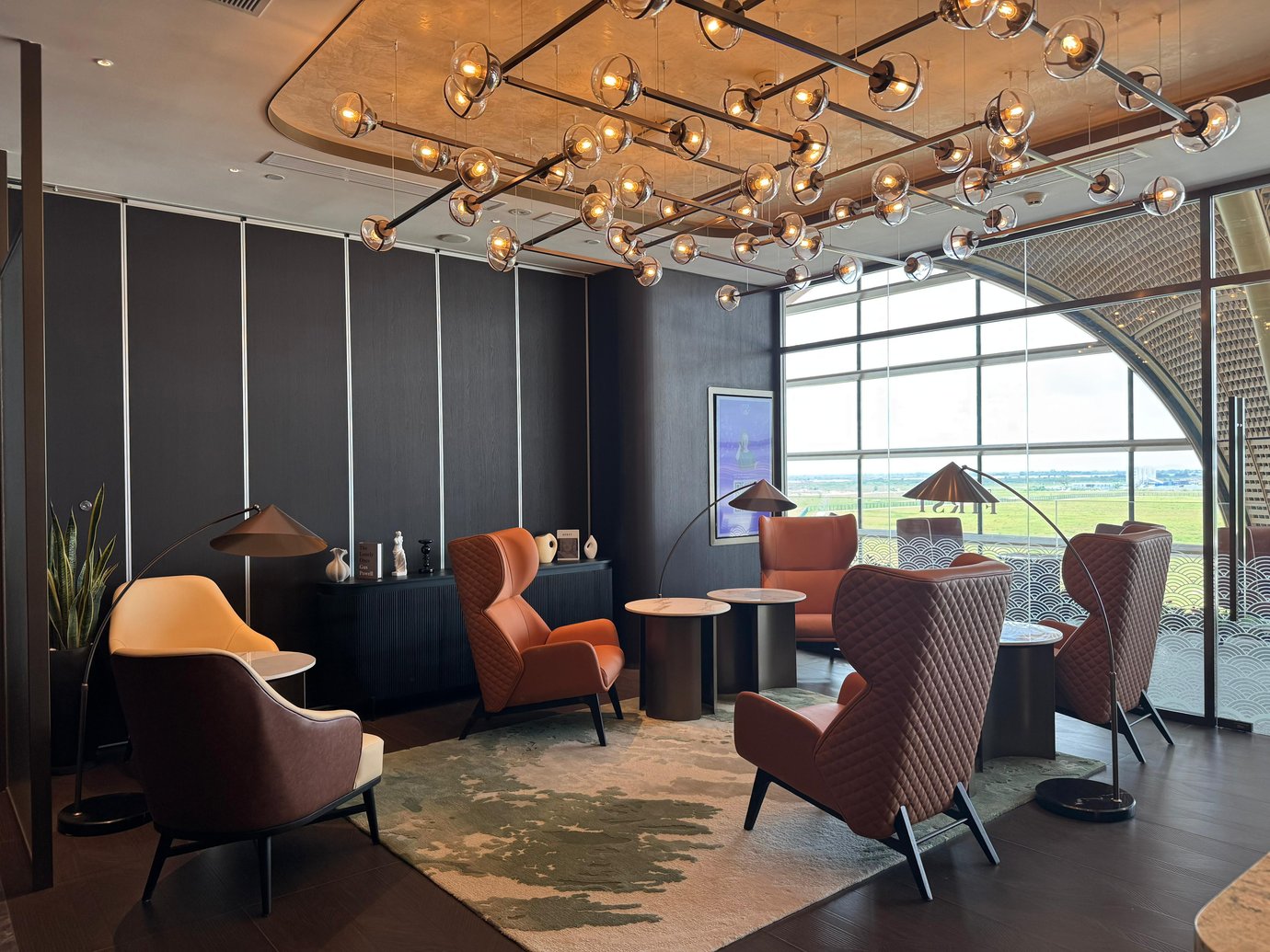 A private seating area in Plaza Premium First Lounge at Techo International Airport features comfortable chairs and tables with views of the airfield.