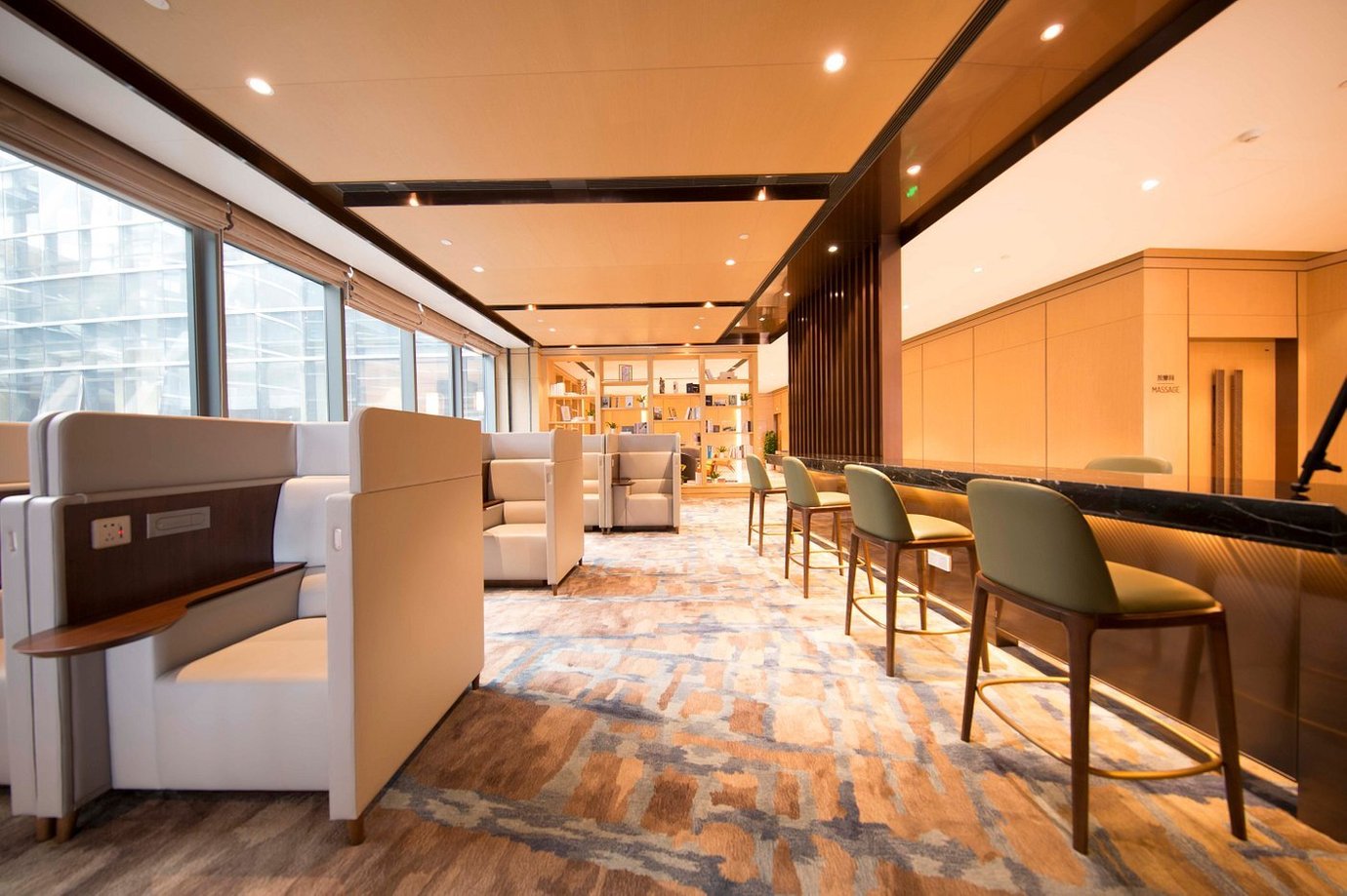 Spacious and well-lit interior of the Plaza Premium VIP Lounge at Qingdao Jiaodong International Airport, featuring elegant seating arrangements with private booths, high bar stools, and modern decor.