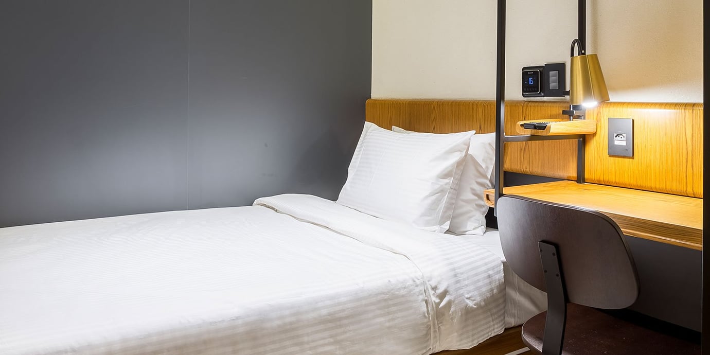 Private relaxation suite at the arrivals Plaza Premium Lounge in Rio de Janeiro GIG Airport, featuring a single bed with crisp white linens, built-in desk, modern lighting, and bedside charging station—ideal for rest between flights.