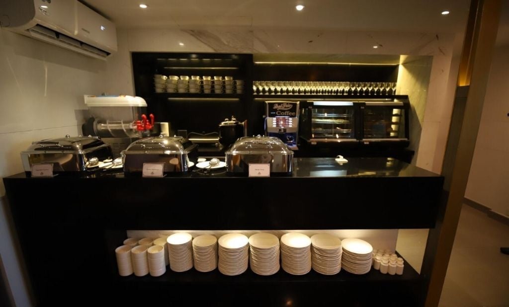 Buffet and beverage station at Majestic Lounge, Jinnah International Airport (KHI), featuring hot food trays, coffee machine, and self-serve dining setup for lounge guests.