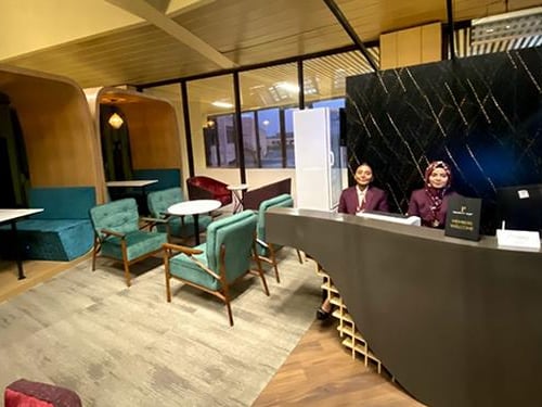 Prestige Lounge reception area at Jinnah International Airport (KHI), featuring modern seating, marble-front desk, and attentive lounge staff welcoming premium passengers.