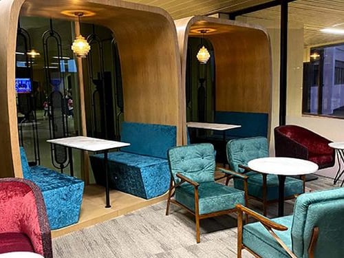 Seating area at Prestige Lounge, Jinnah International Airport (KHI), featuring teal armchairs, private booth-style seating, and modern décor for departing passengers.