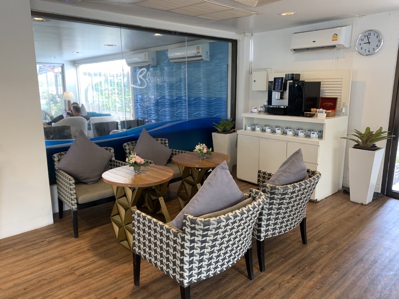 Seating and beverage area inside USM Blue Ribbon Lounge (Domestic), featuring cushioned armchairs around small round tables.