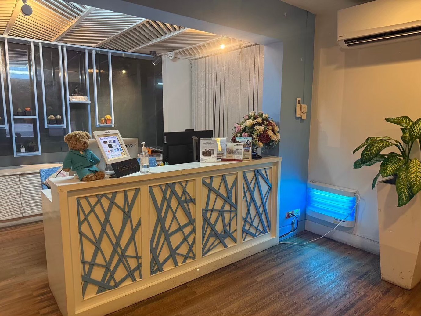 Reception desk at USM Blue Ribbon Lounge (Domestic), featuring a check-in counter with a touchscreen terminal, decorative paneling, flowers, and lounge entry area details.