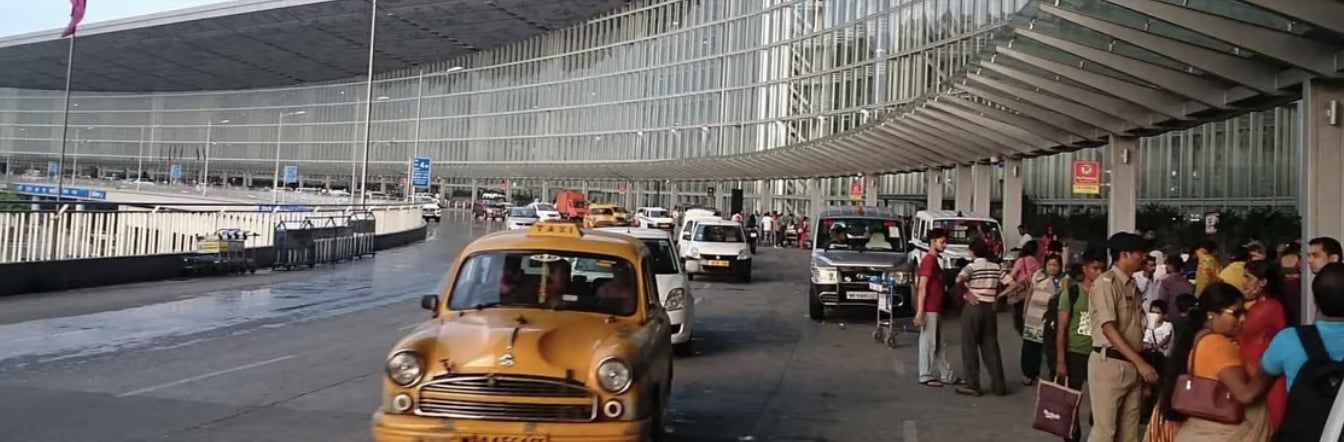 Exterior view of Kolkata Netaji Subhas Chandra Bose International Airport (CCU) with iconic yellow taxis at the departures drop-off.