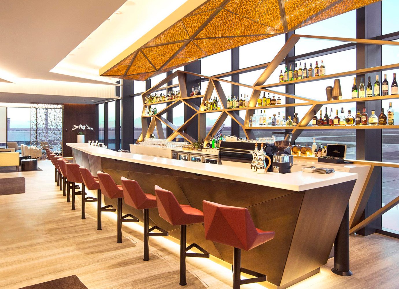 Aspire Lounge bar at Melbourne Airport with geometric shelving, amber lighting, and a full selection of spirits.