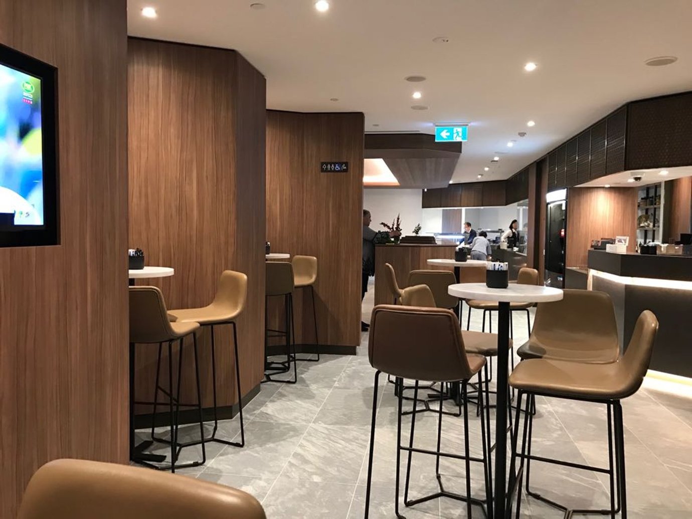 Plaza Premium Lounge Melbourne Airport seating area with modern tables and bar-style chairs.