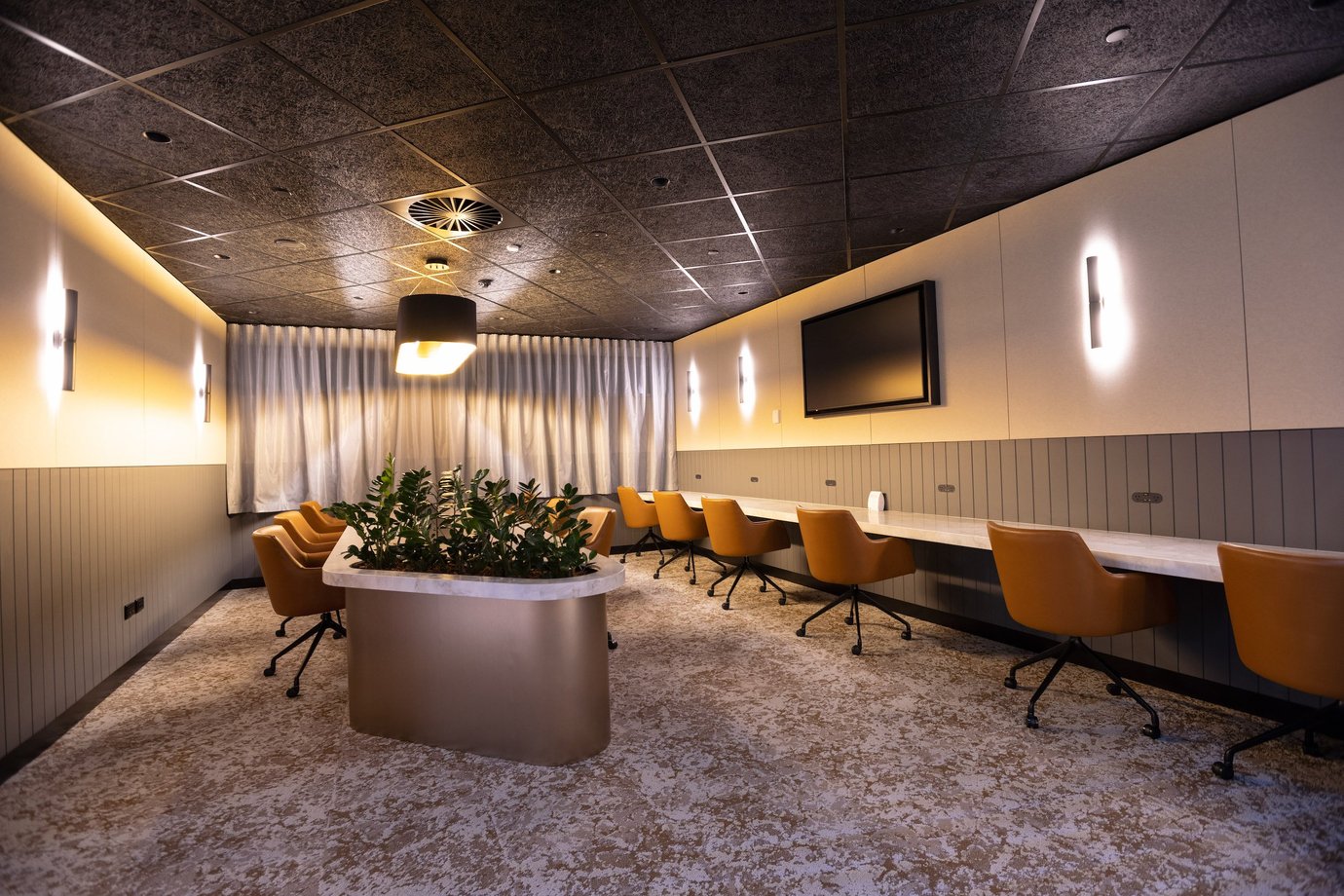 Work and relaxation area inside Aspire Lounge Perth Airport featuring individual workstations, swivel chairs, charging access, and soft ambient lighting