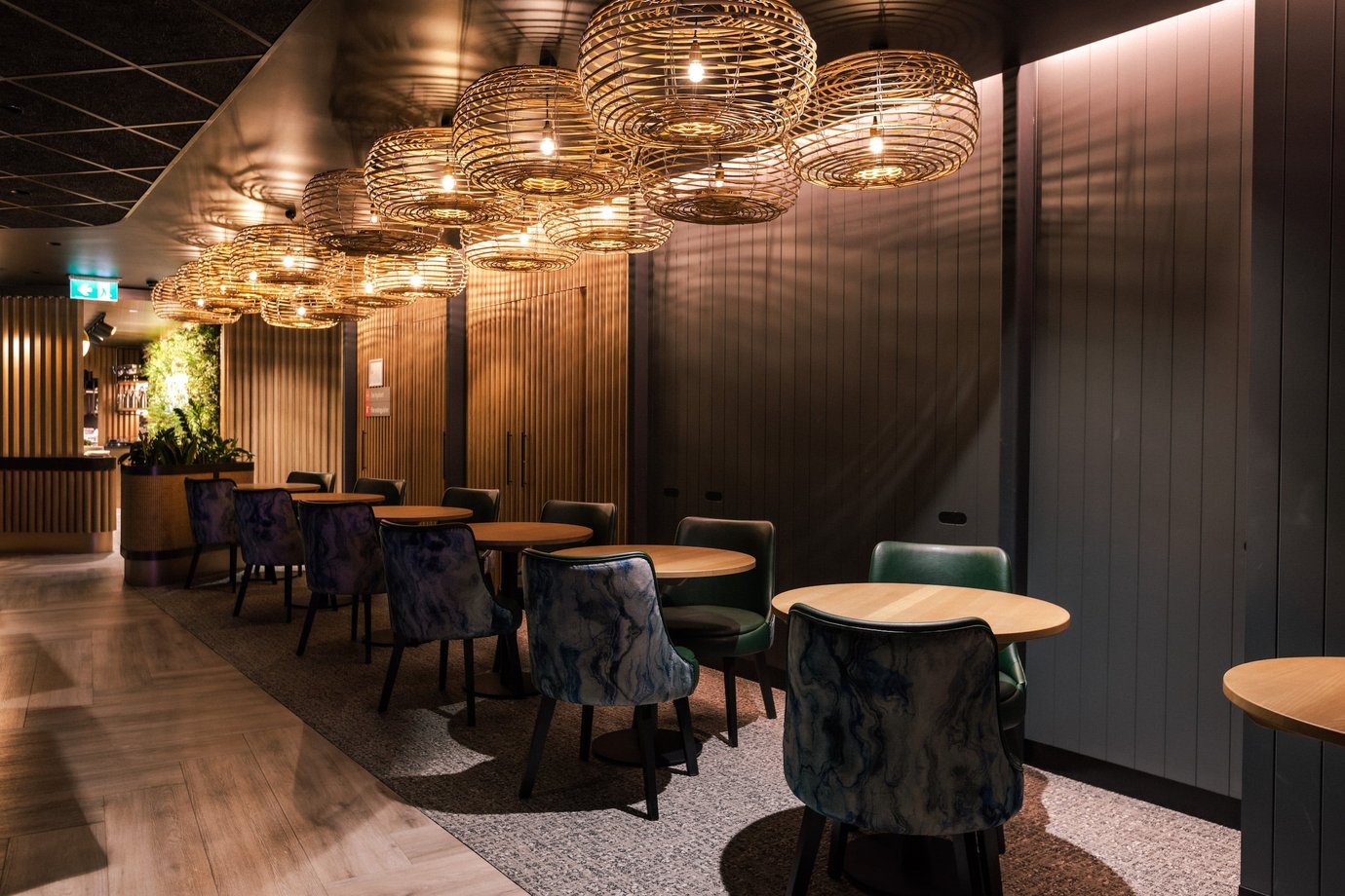 Modern seating area at Aspire Lounge Perth Airport featuring intimate dining tables, designer pendant lighting, timber finishes, and comfortable lounge seating.