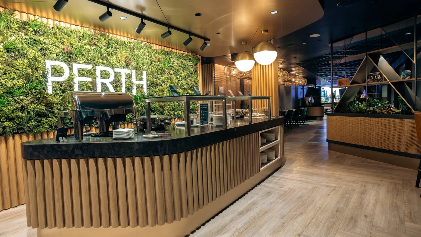 Buffet dining area at Aspire Lounge Perth Airport featuring fresh food selections, hot meal stations, modern timber finishes, and ambient lighting.
