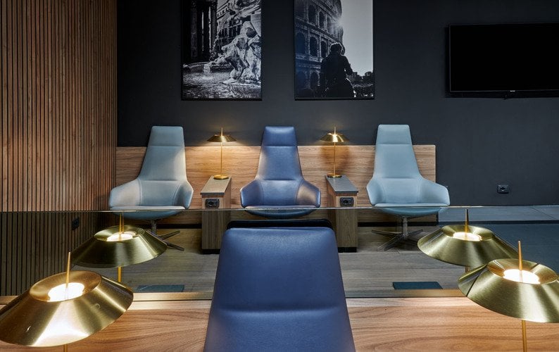 Seating area in Prima Vista Lounge at Leonardo da Vinci-Fiumicino Airport features individual chairs with side tables and reading lamps. Seating area in Prima Vista Lounge at Leonardo da Vinci-Fiumicino Airport features individual chairs with side tables and reading lamps.