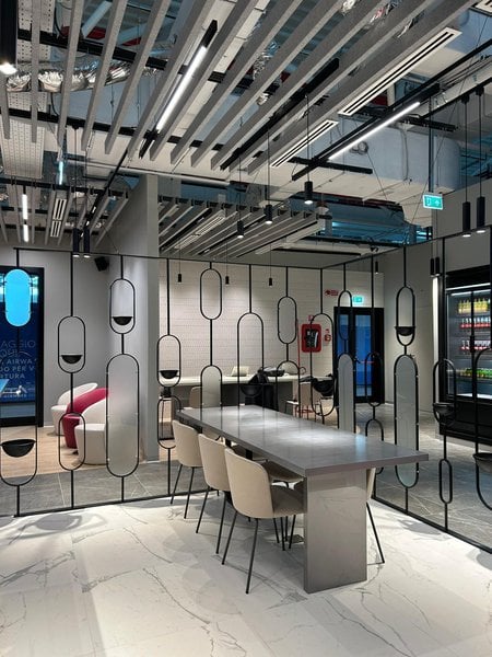 The Primeclass Lounge at Leonardo da Vinci-Fiumicino Airport features a communal table with seating and a partitioned area for privacy. The Primeclass Lounge at Leonardo da Vinci-Fiumicino Airport features a communal table with seating and a partitioned area for privacy.