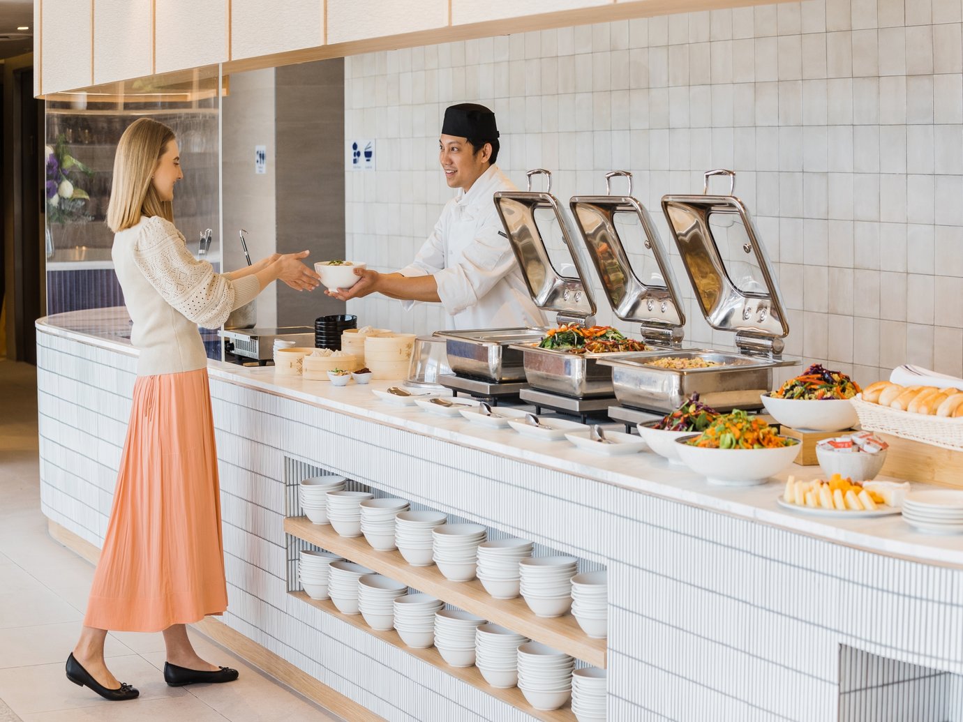 SkyTeam Lounge at Sydney Airport buffet area, guest receiving a dish from a chef with hot food stations, salads, and plated options along the counter.