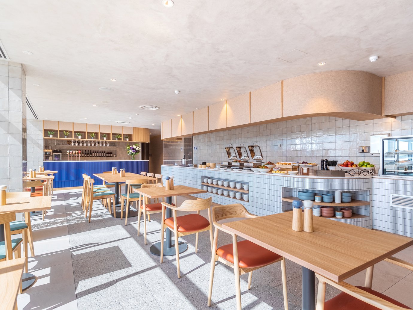SkyTeam Lounge at Sydney Airport dining area with buffet counter, hot food stations, and light-filled seating with wooden tables and chairs.
