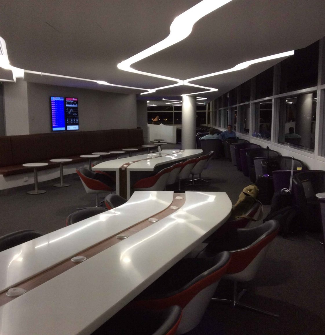 Virgin Australia Lounge at Sydney Airport seating area with communal work tables, modern lighting, and runway views through large windows.