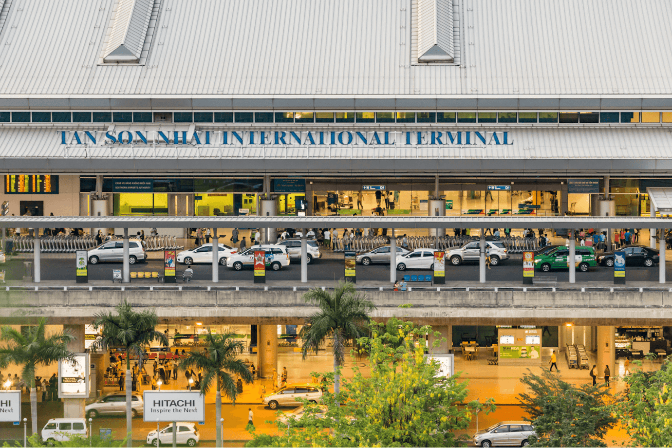 Exterior view of Tan Son Nhat International Terminal in Ho Chi Minh City, showing multiple levels with taxis, passengers, and terminal signage.